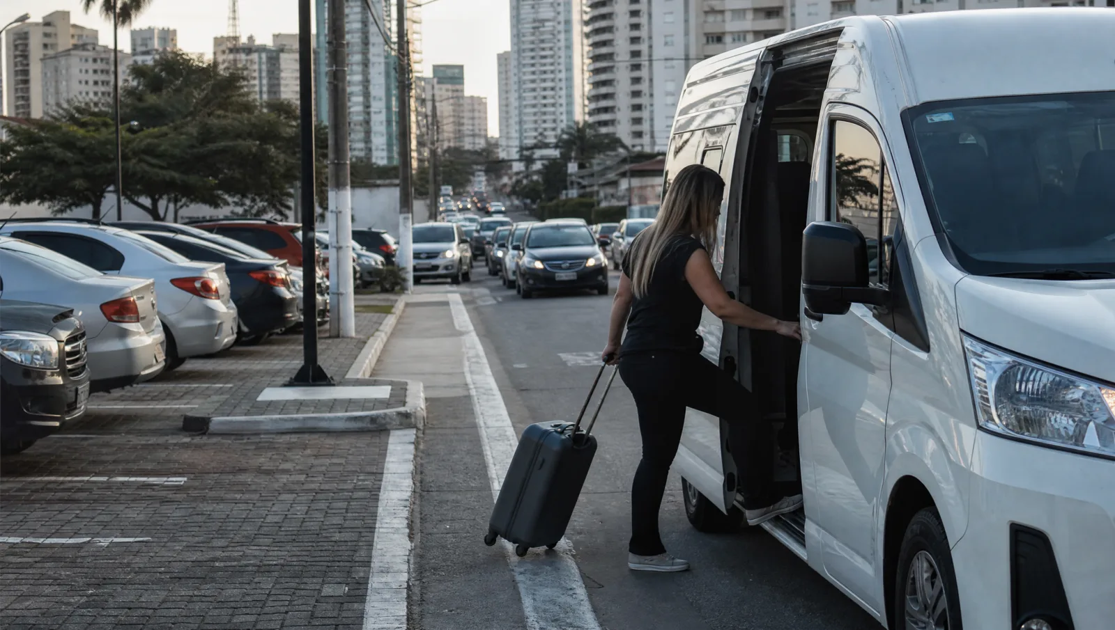 Van de traslado recolhendo passageiro em rua movimentada perto do terminal de Congonhas, no caminho do estacionamento barato