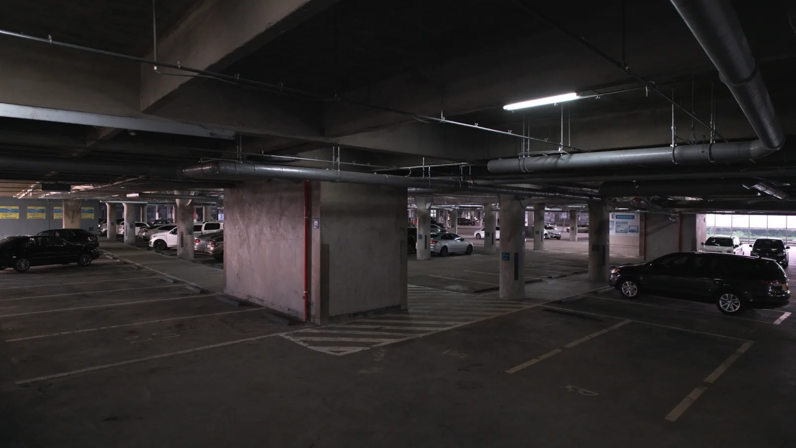 Interior de edifício garagem coberto, com colunas de concreto e vagas marcadas